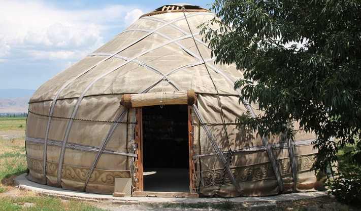 A yurt on a permanent foundation Picture of a yurt on a permament foundation, with a tree to the right and grass to the left.
Taken from https://buildgreennh.com/yurt-houses/